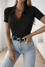 Person wearing a black top and light blue jeans with a blurred background