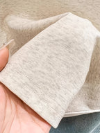Close-up of beige fabric held by a hand on a neutral background