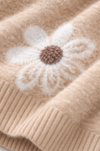 Close-up of a beige knitted fabric with a white flower design.