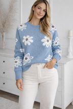 Woman wearing a blue sweater with white floral patterns in a room.