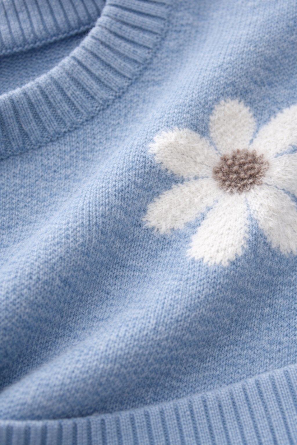 Close-up of a blue sweater with a white flower design.
