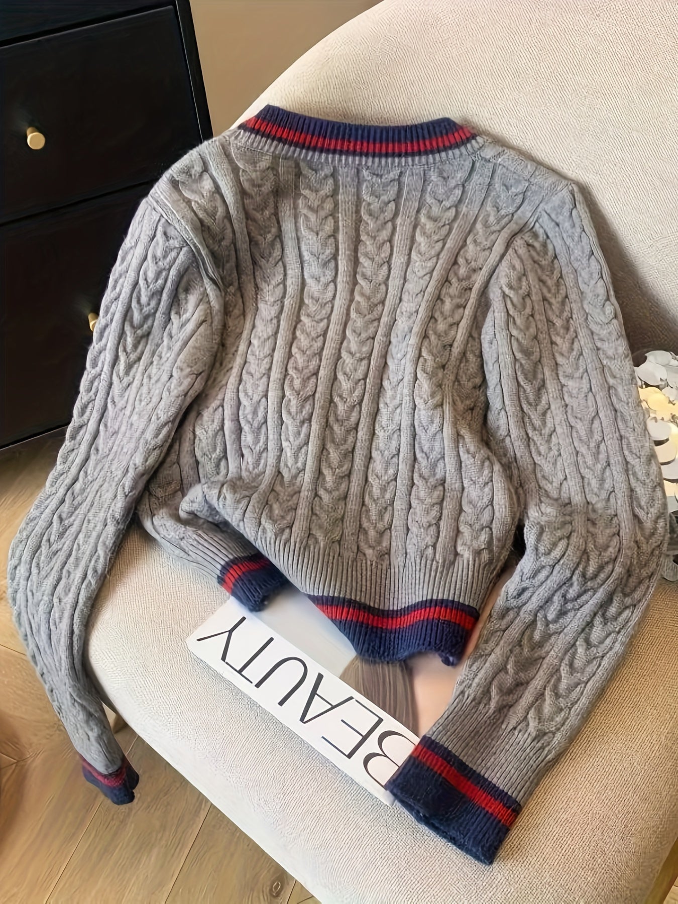 Gray cable knit sweater with blue and red accents on a chair
