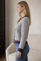Woman wearing a cable knit cardigan with a neutral background