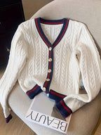 White cable knit cardigan with blue and red trim on a chair
