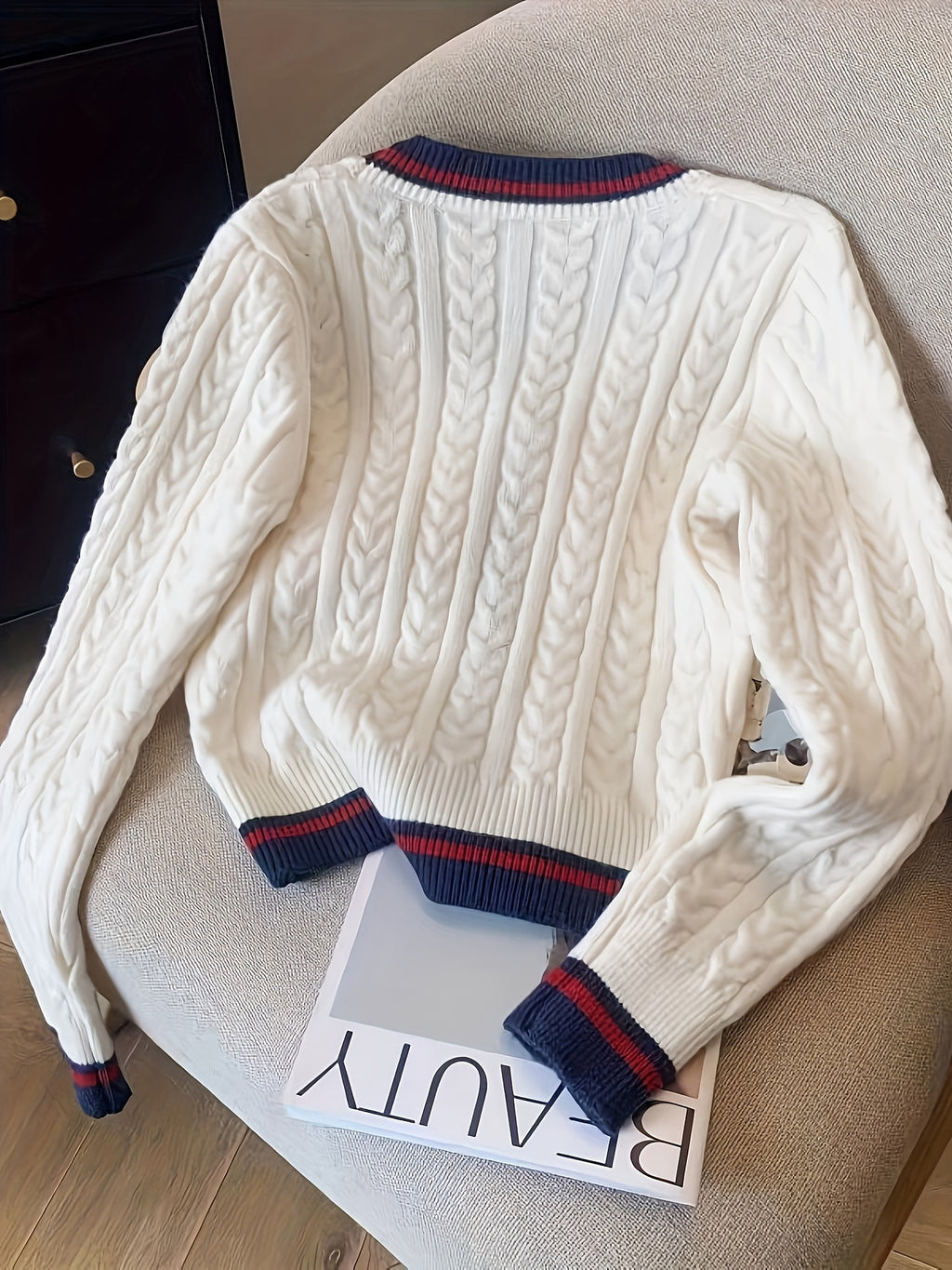 White cable knit sweater with blue and red accents on a chair