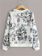 Floral patterned sweatshirt on a wooden hanger against a gray background