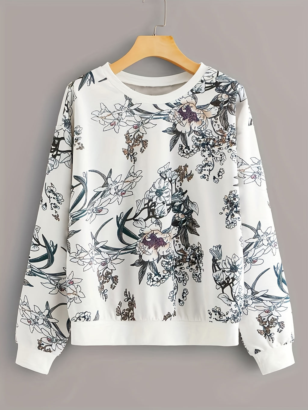 Floral-patterned sweatshirt on a hanger against a gray background