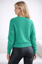 Woman wearing a green sweater with heart patterns on a white background