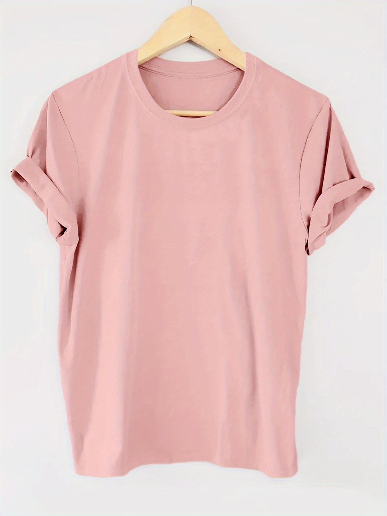 Pink t-shirt on a wooden hanger against a white background
