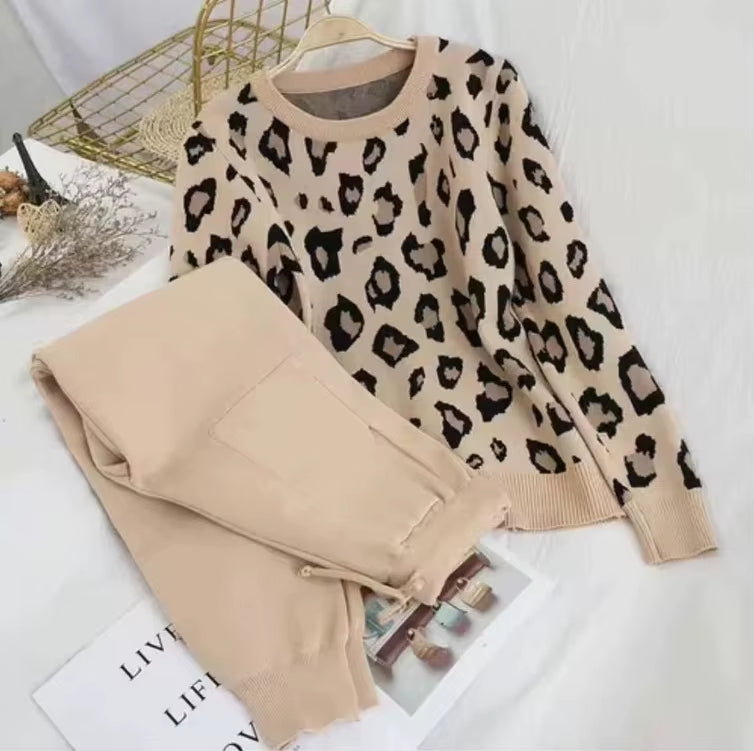 Leopard print sweater and beige pants on a white surface with a magazine underneath.