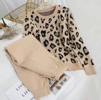 Leopard print sweater and beige pants on a white surface with a magazine underneath.