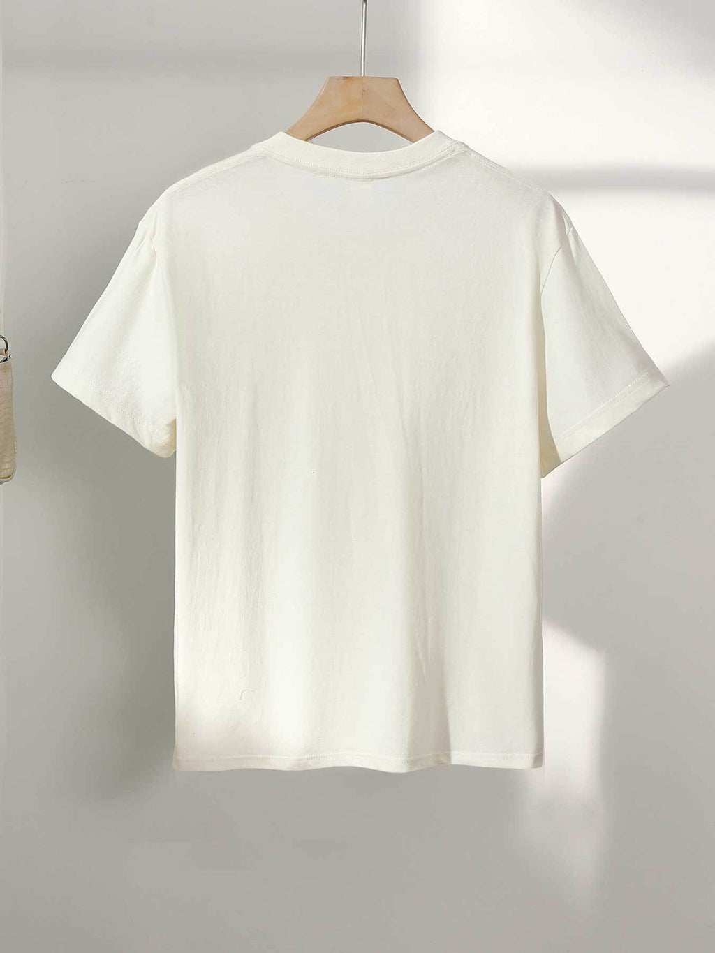 White t-shirt on a hanger against a light gray background