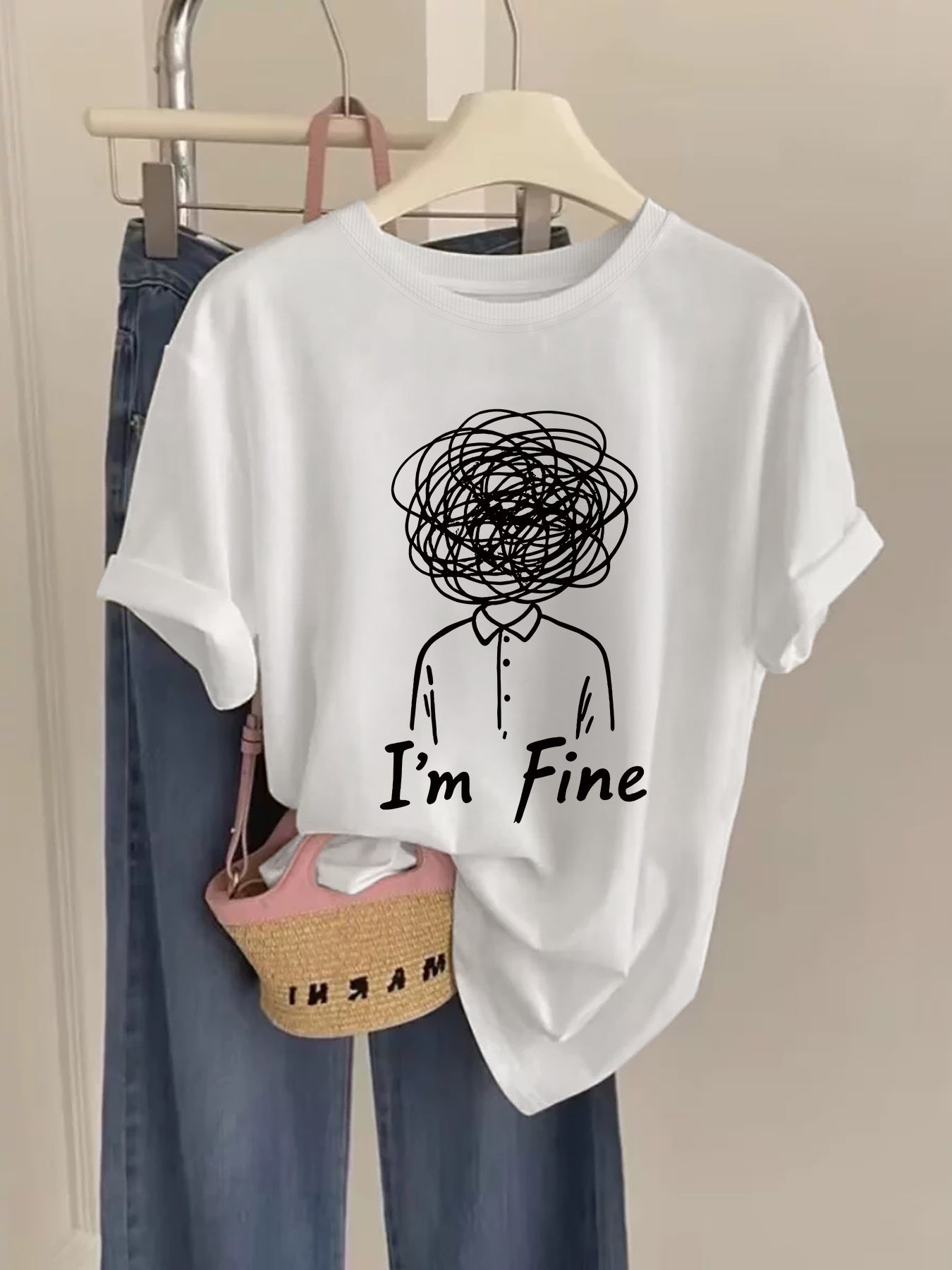 White t-shirt with a graphic and 'I'm Fine' text on a hanger with jeans and a basket.