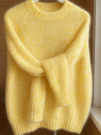 Yellow sweater on a hanger against a wooden wall.