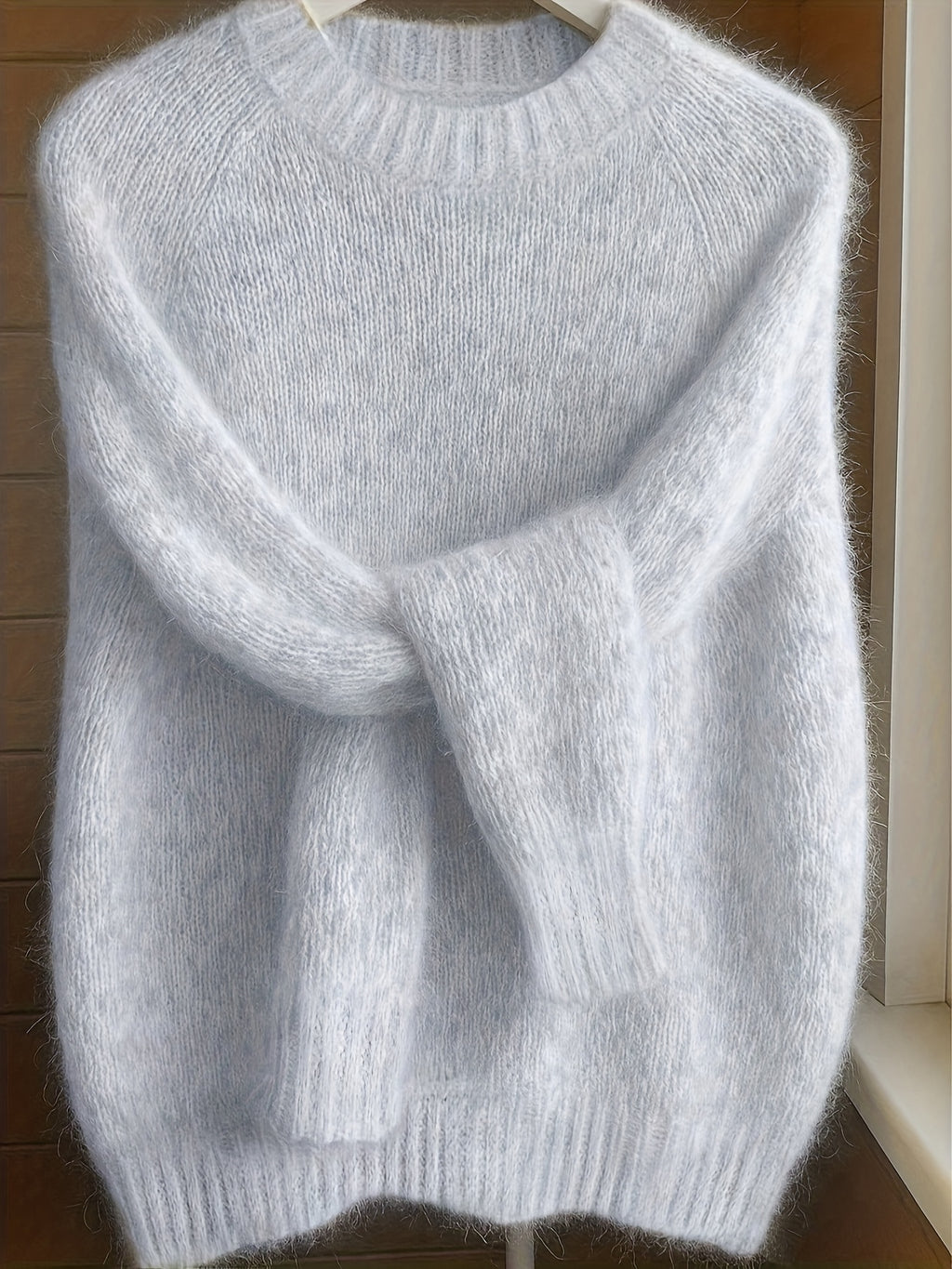 Gray sweater on a hanger against a wooden background