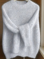 Gray sweater on a hanger against a wooden background