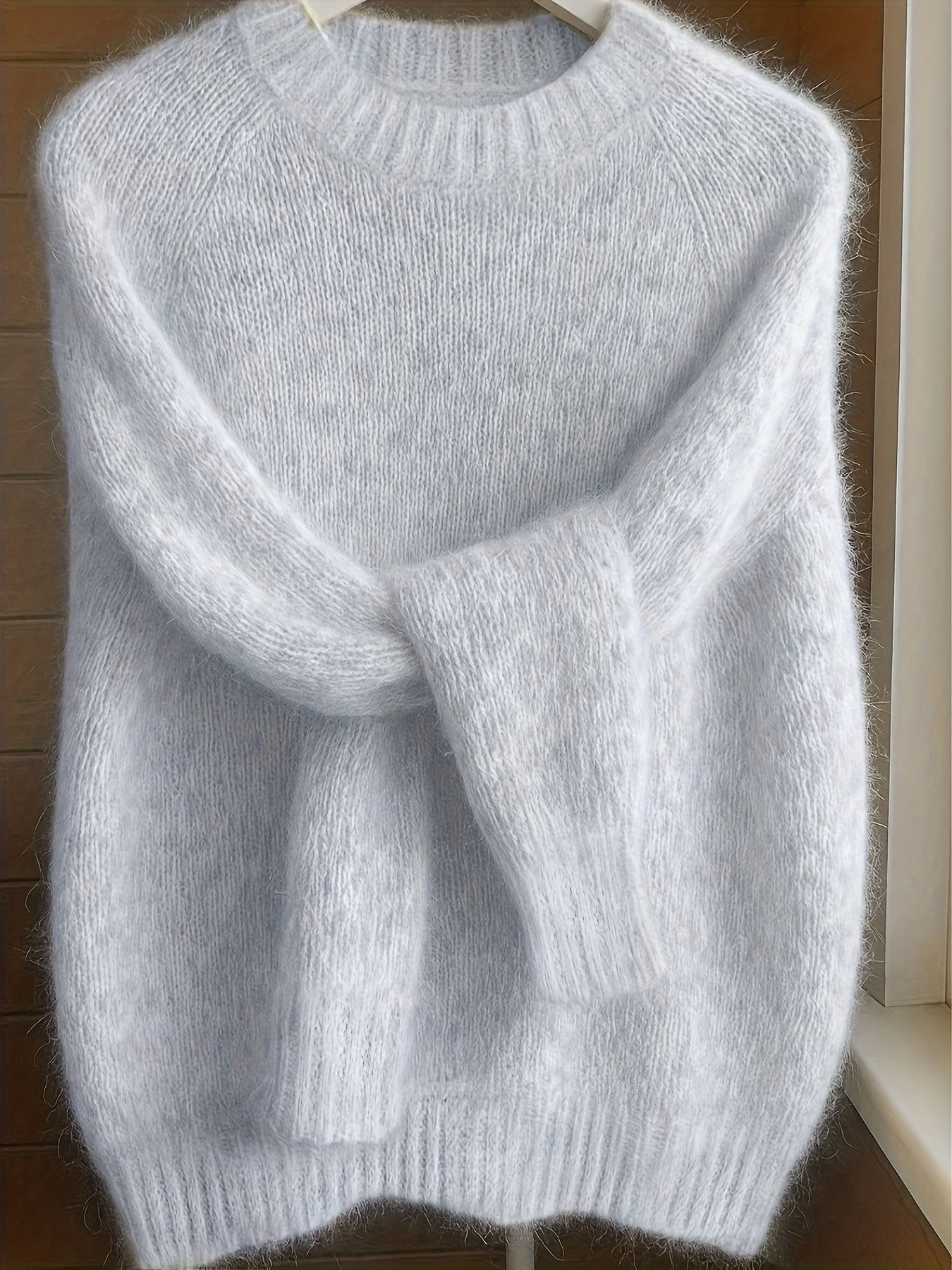Gray sweater on a hanger against a wooden background