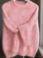 Pink sweater on a hanger against a neutral background