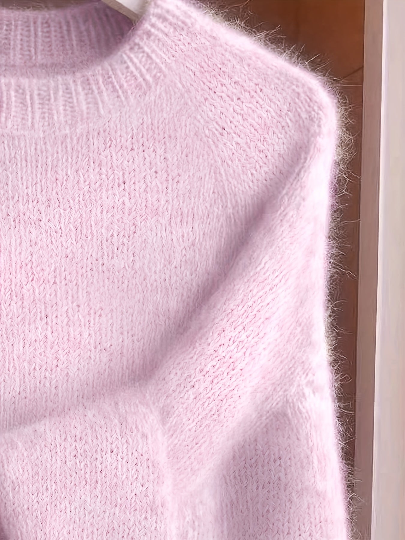 Close-up of a pink knitted sweater on a hanger.