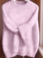 Light purple sweater on a hanger against a wooden background