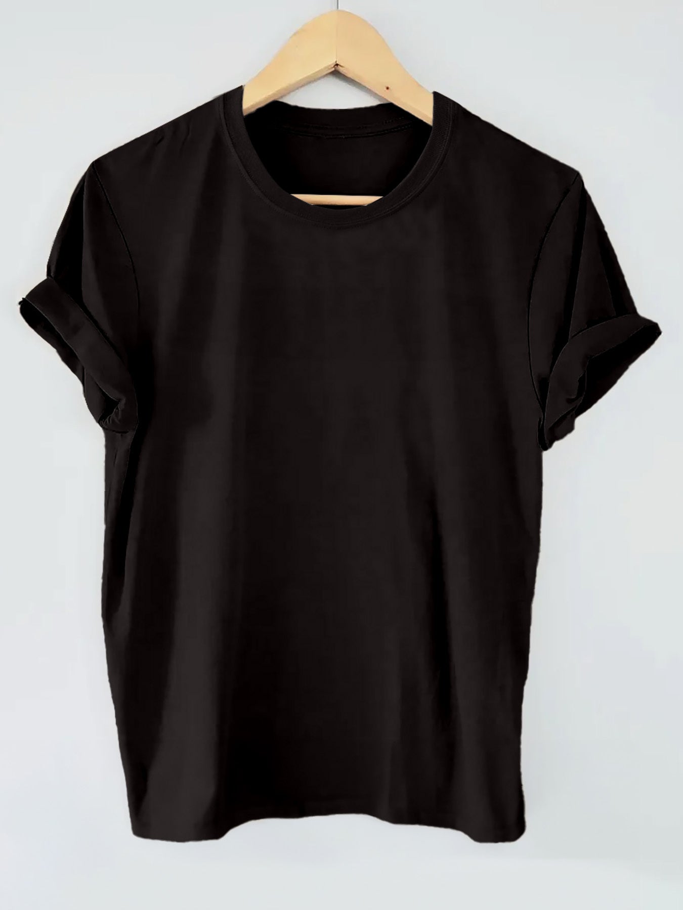 Black t-shirt on a wooden hanger against a light gray background