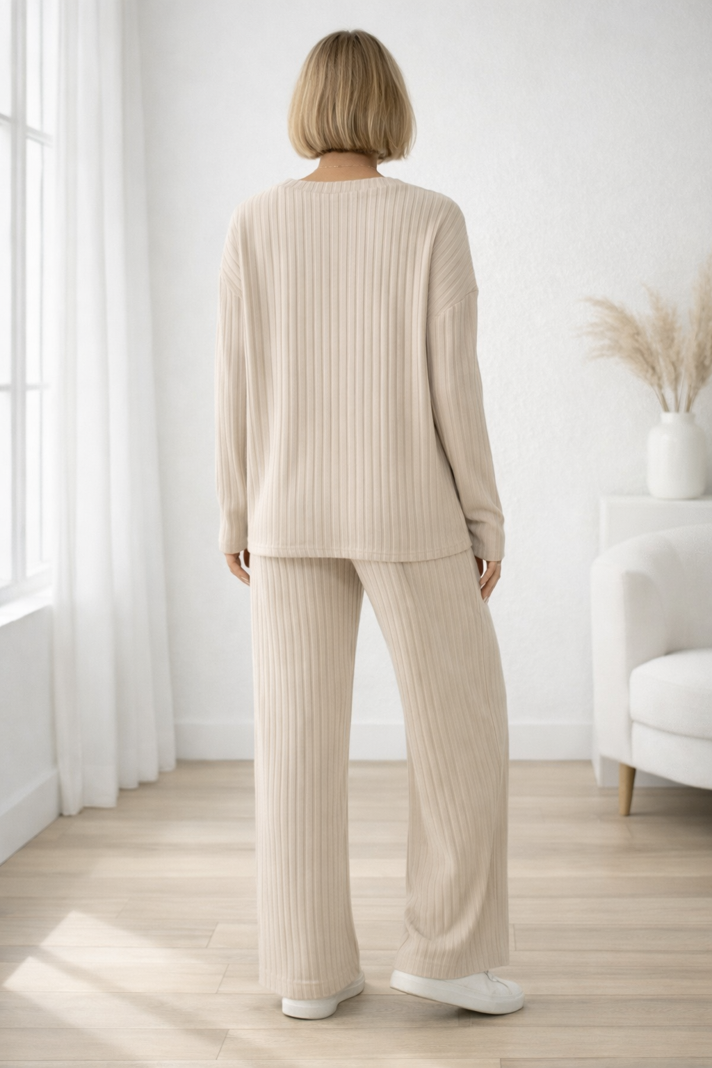 Person wearing a beige ribbed knit outfit in a bright room with white walls and wooden floor.