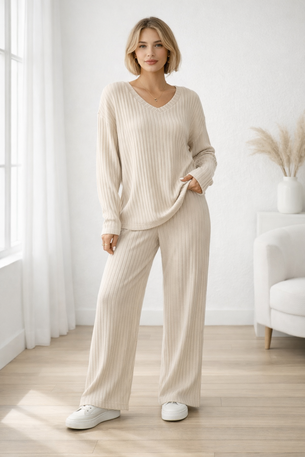 Woman wearing a beige ribbed lounge set in a bright room with white walls and wooden floor.