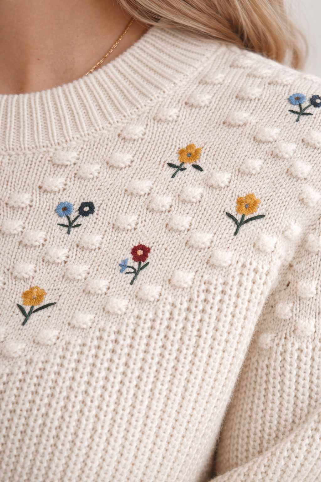 Close-up of a beige sweater with floral embroidery
