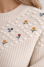 Close-up of a beige sweater with floral embroidery