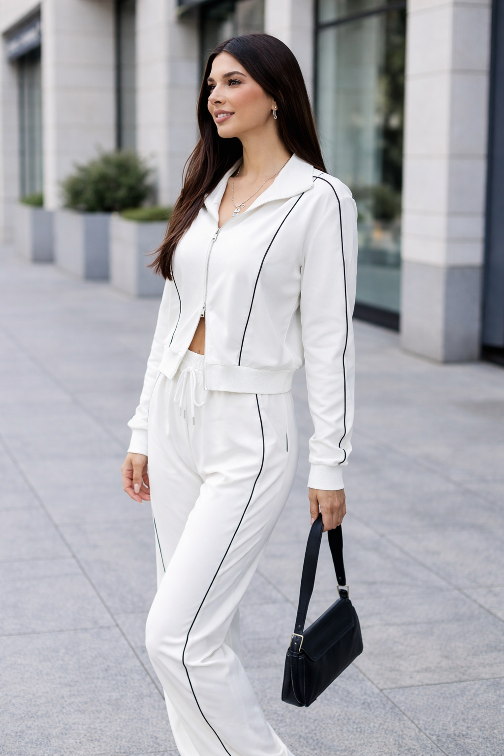 Woman in a white outfit with black accents walking on a city street.