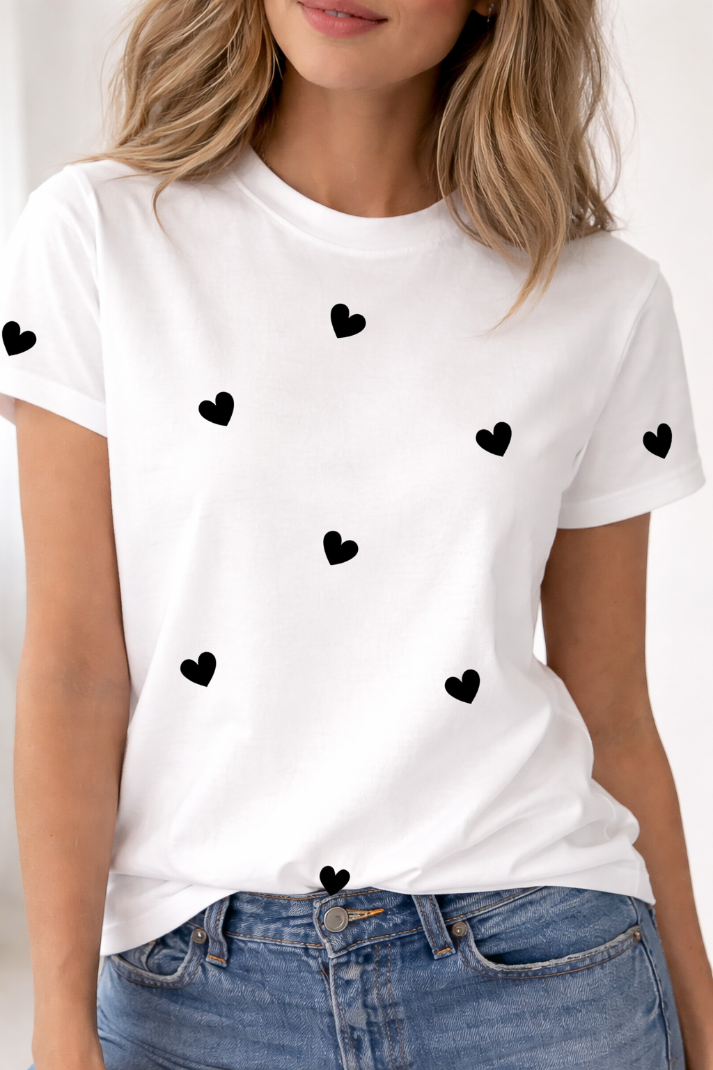White t-shirt with black heart patterns worn by a person, against a neutral background