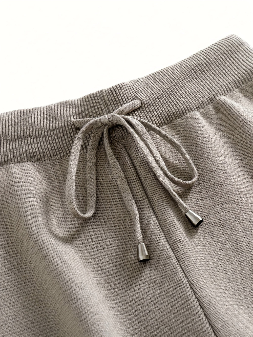 Close-up of gray sweatpants with a drawstring on a white background