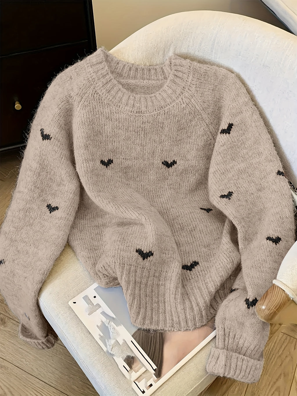 Beige sweater with black heart patterns on a chair