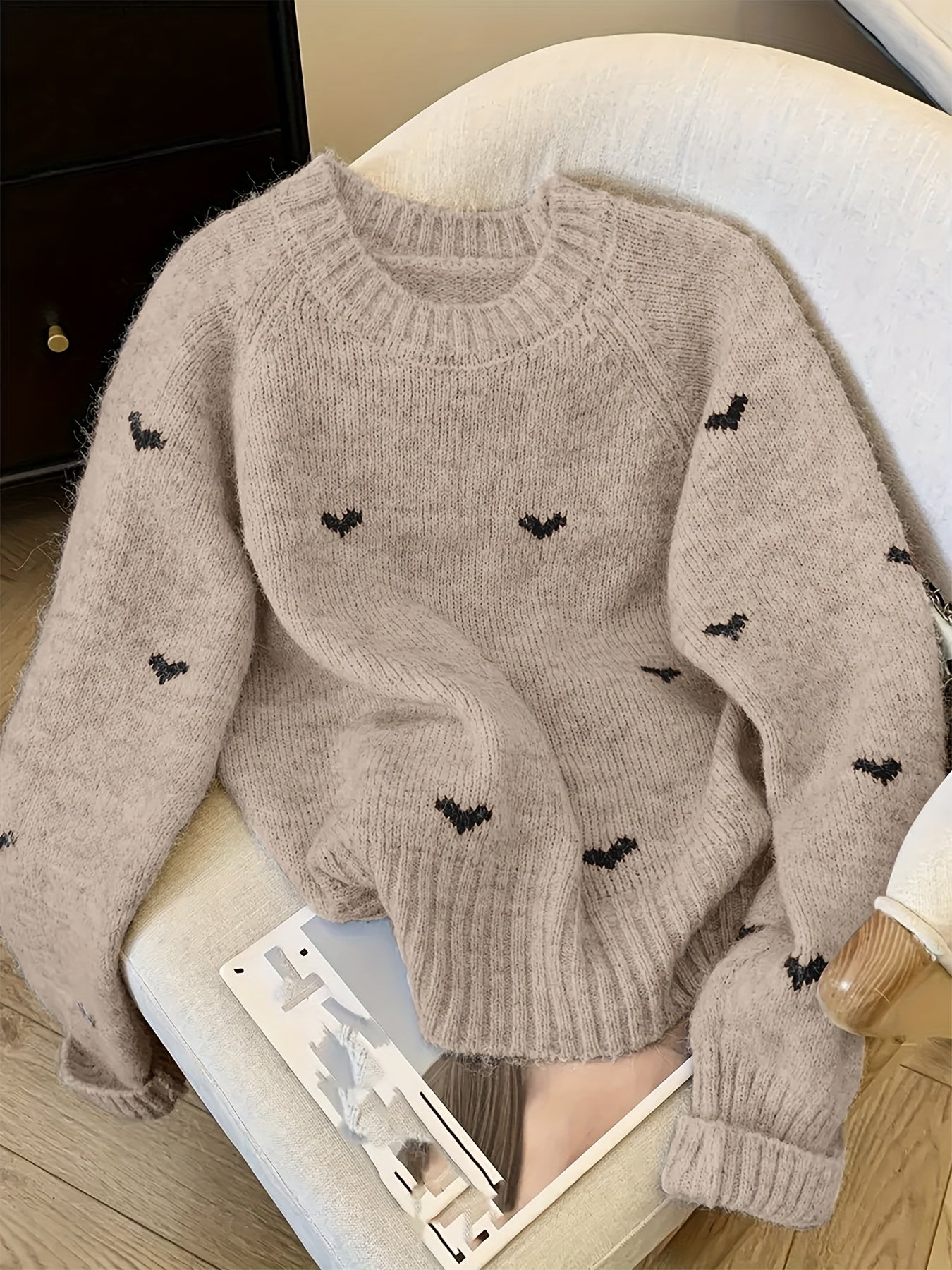 Beige sweater with black heart patterns on a chair