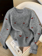 Gray sweater with red heart patterns on a chair