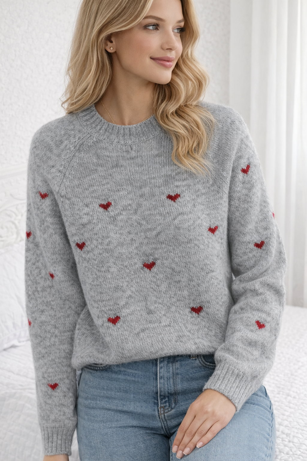 Woman wearing a gray sweater with red heart patterns against a white background