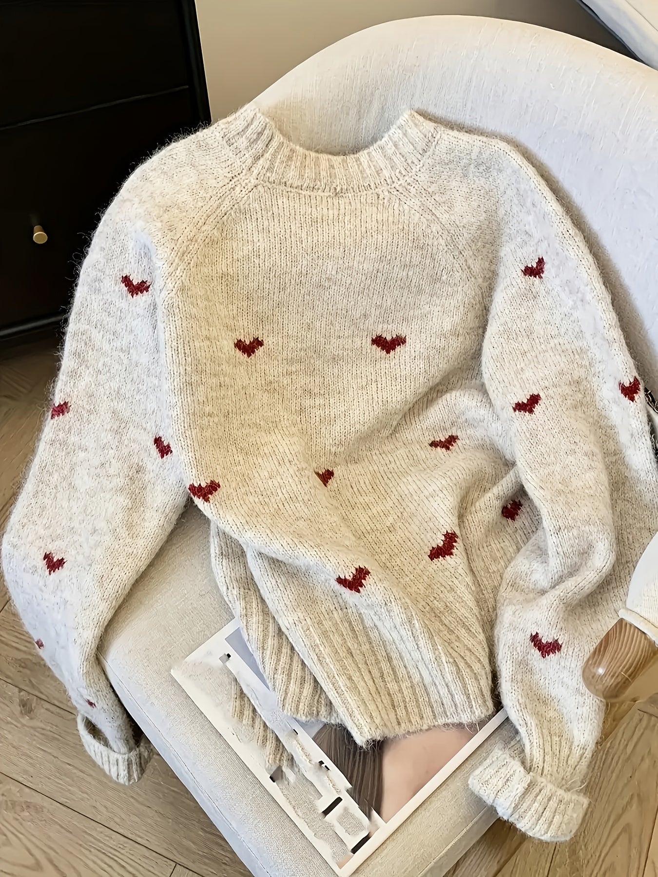 Beige sweater with red heart patterns on a chair