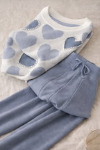 Light blue heart-patterned sweater and pants set on a beige surface