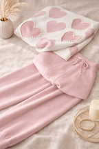 Pink heart-patterned outfit on a light surface with decorative elements.