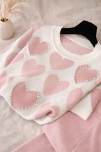 Pink sweater with heart patterns on a beige surface