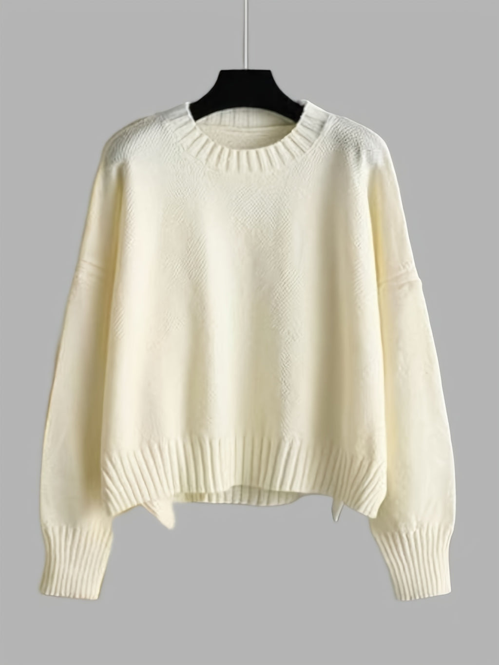 White sweater on a hanger against a gray background