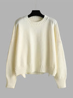 White sweater on a hanger against a gray background