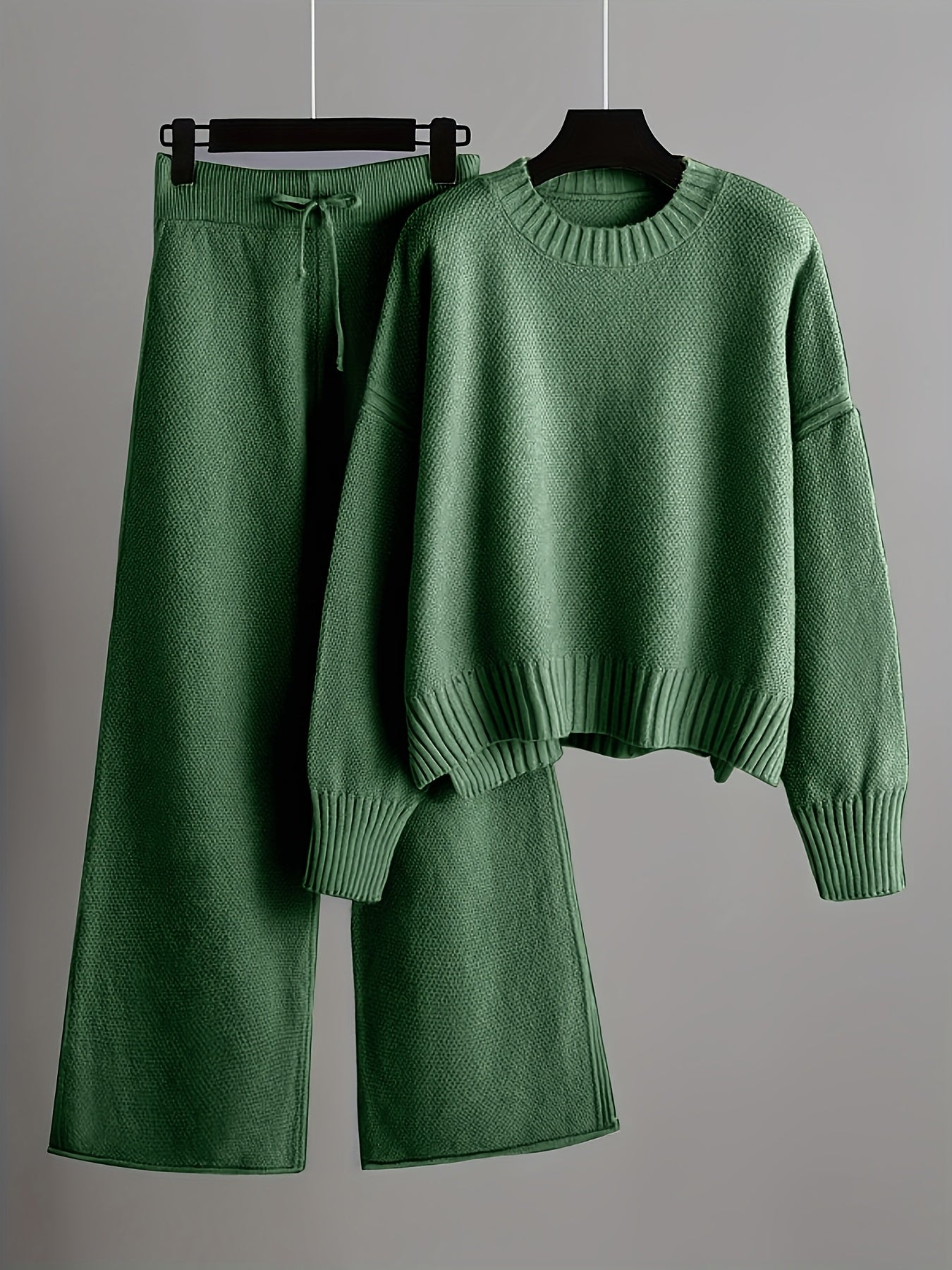Green sweater and shorts set on hangers against a gray background