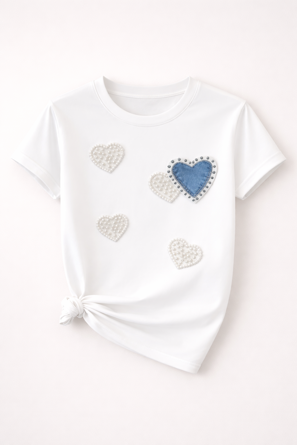 White t-shirt with heart-shaped decorations on a light pink background