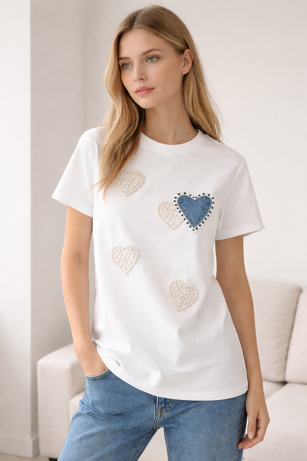 Woman wearing a white t-shirt with heart designs in a living room setting