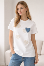 Woman wearing a white t-shirt with heart designs in a living room setting