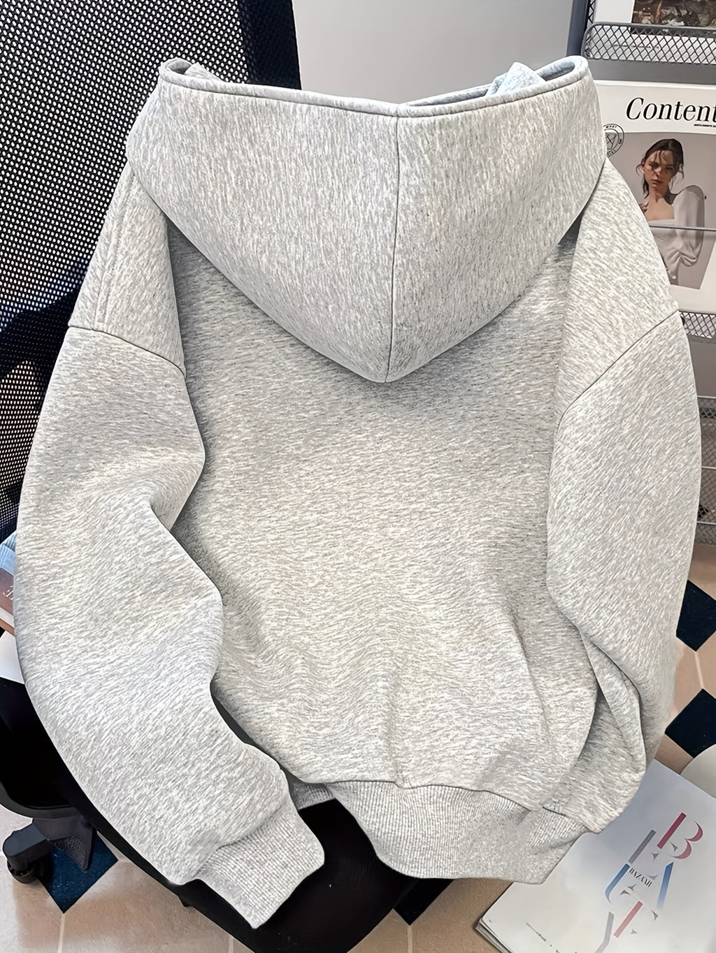 Gray hoodie on a chair with a magazine in the background