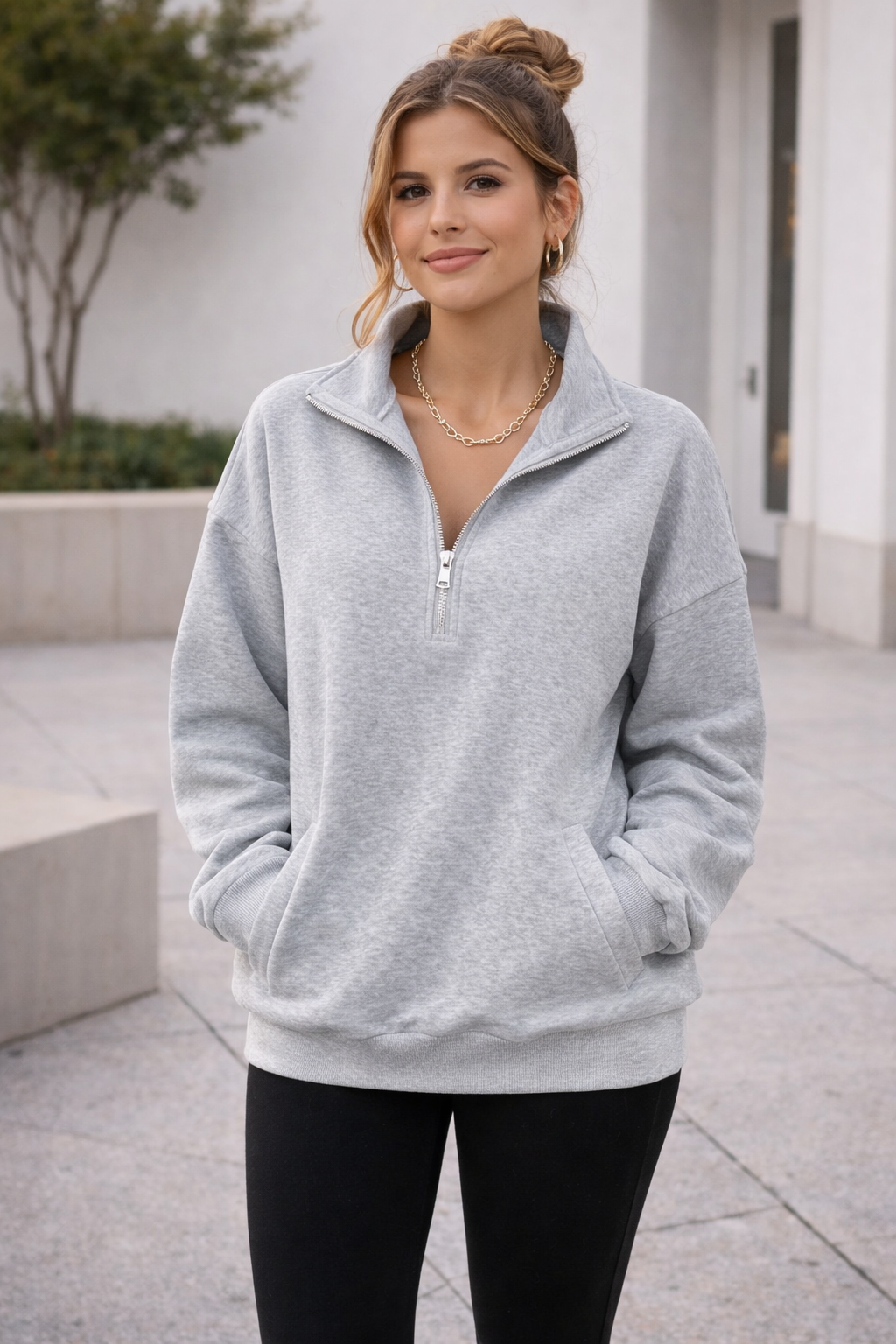 Woman wearing a gray pullover with a zipper outdoors.