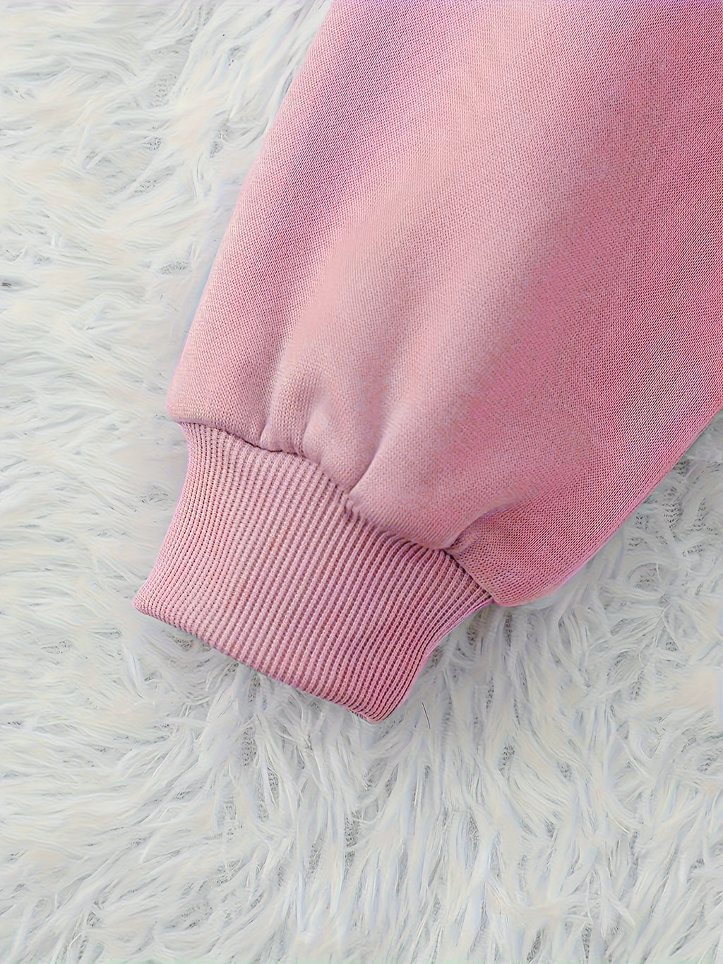 Close-up of a pink sweatshirt on a white fluffy surface