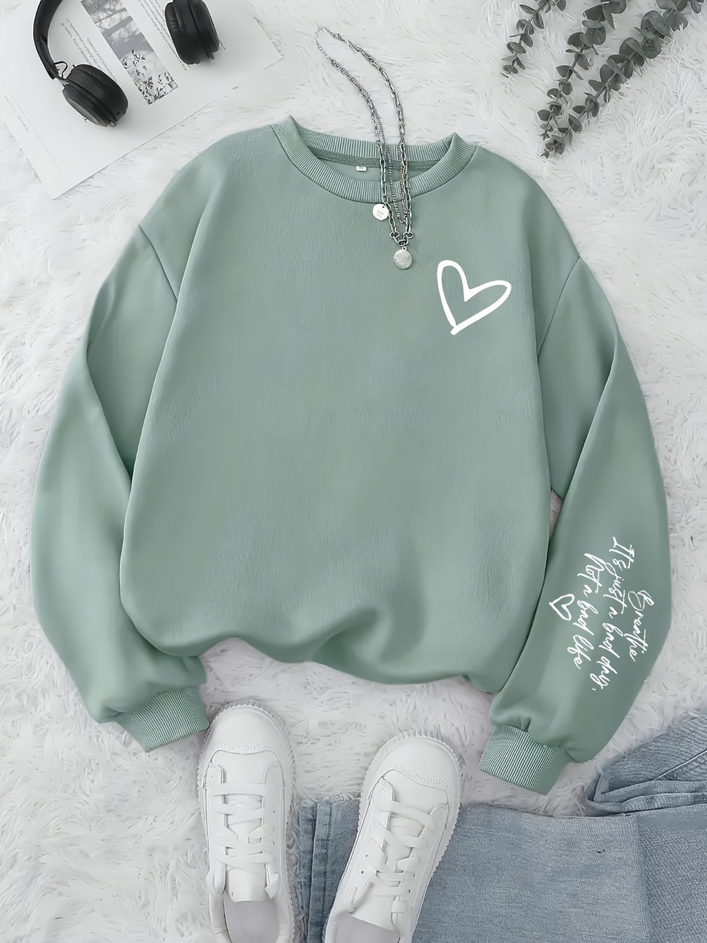 Green sweatshirt with a heart design on a light gray surface